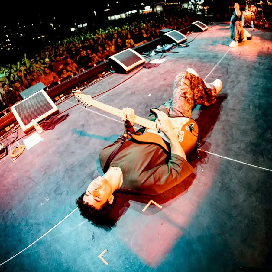 townsend lying on his back on stage, still playing guitar, crowd behind him