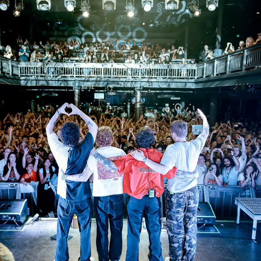 the band taking a bow, arms around each other, facing a packed two-level venue