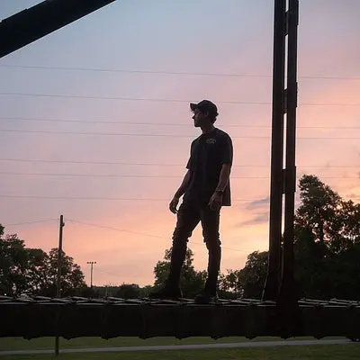 townsend in silhouette standing on a bridge rail under power lines